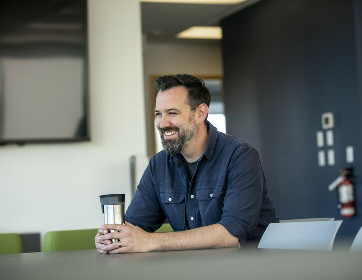 a male team member sitting in the office Lounge, smiling