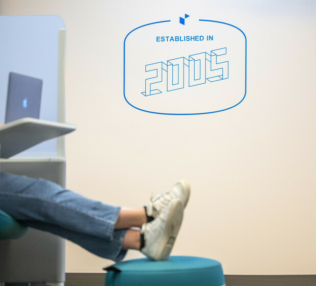 a team member working on a laptop in a pod chair, with the decal on the wall in the background that reads "established in 2005"