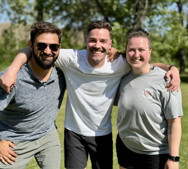 3 team members smiling together outdoors